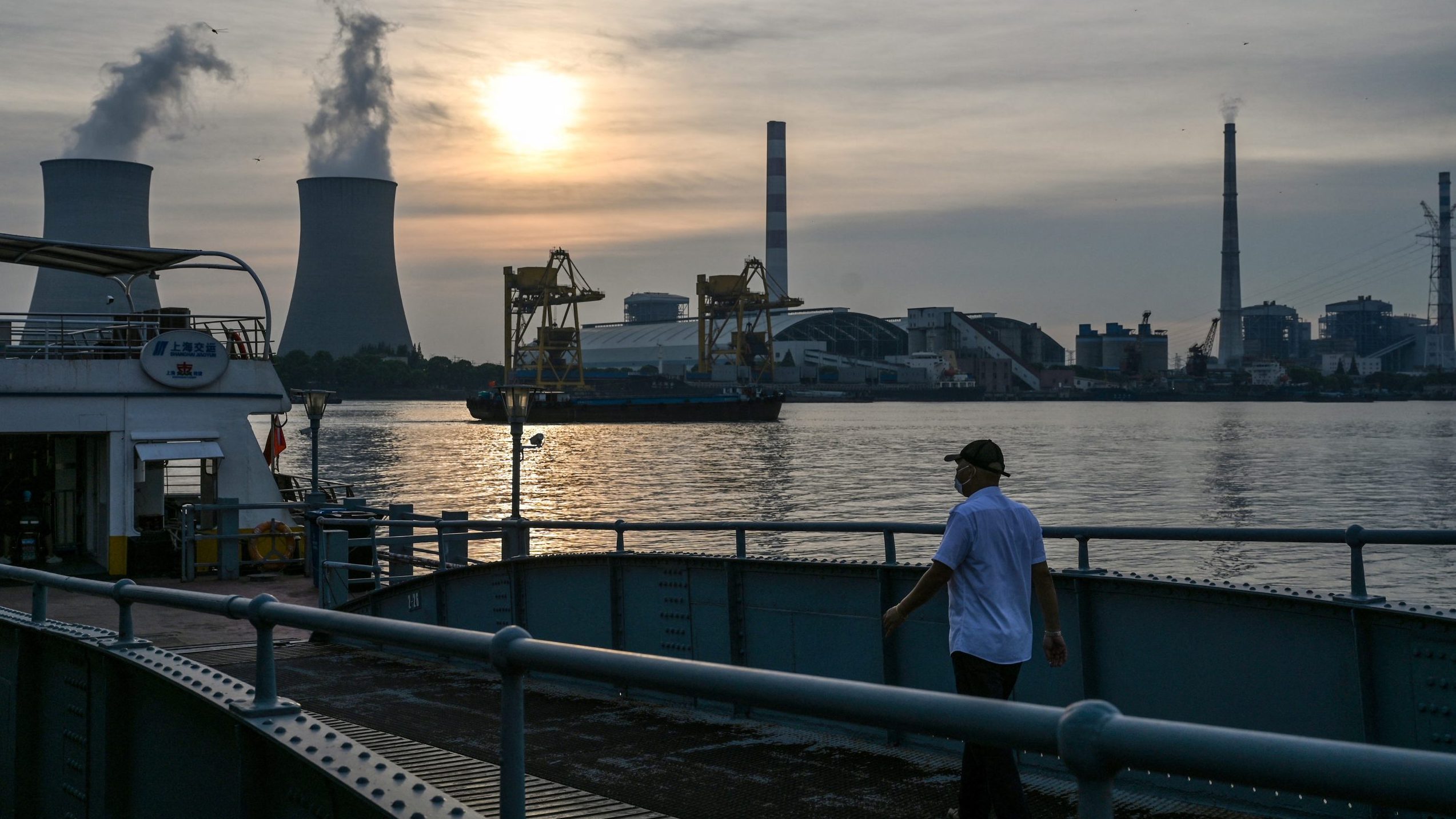 A man walks towards a ferry as the Wujing coal-electricity power station is seen across the Huangpu River in the Minhang district of Shanghai. Getty Images photo